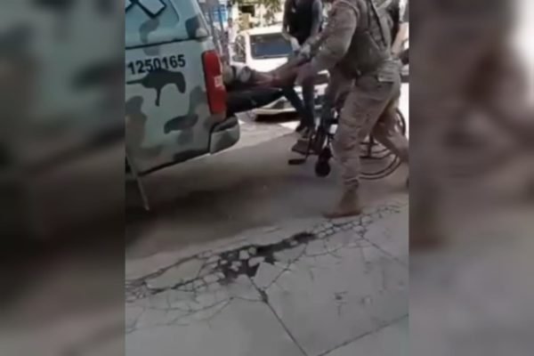 Policial militar de Pernambuco puxa de dentro da viatura o corpo de um suspeito pelos tornozelos