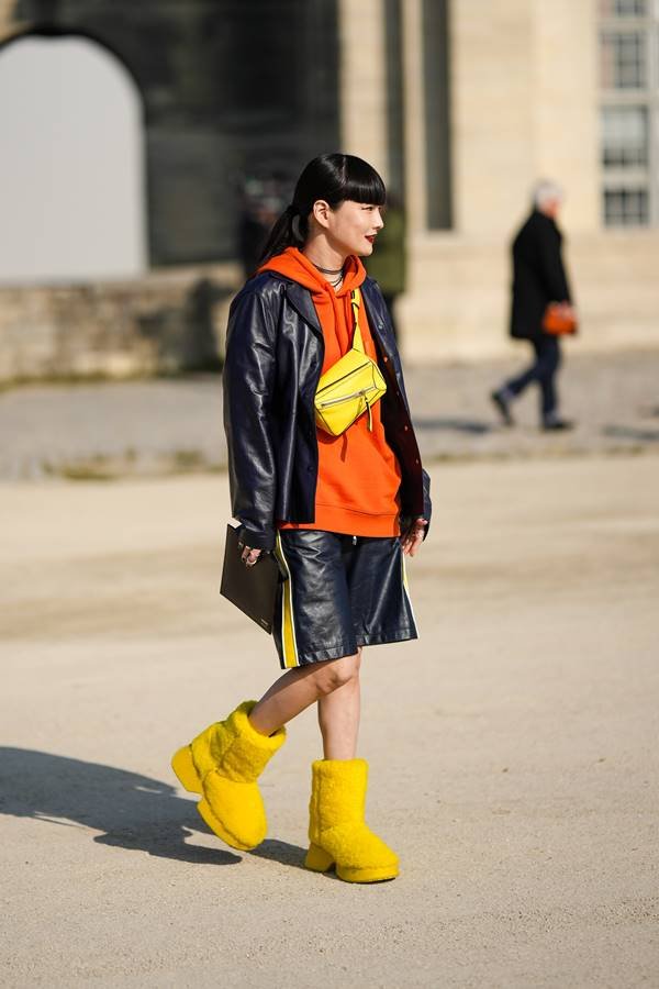 Woman wears orange sweatshirt, black leather jacket and fuzzy yellow boots - Metrópoles