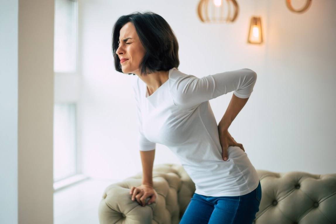 Foto ilustrativa de mulher com dor nas costas provocada por doença renal - Metrópoles