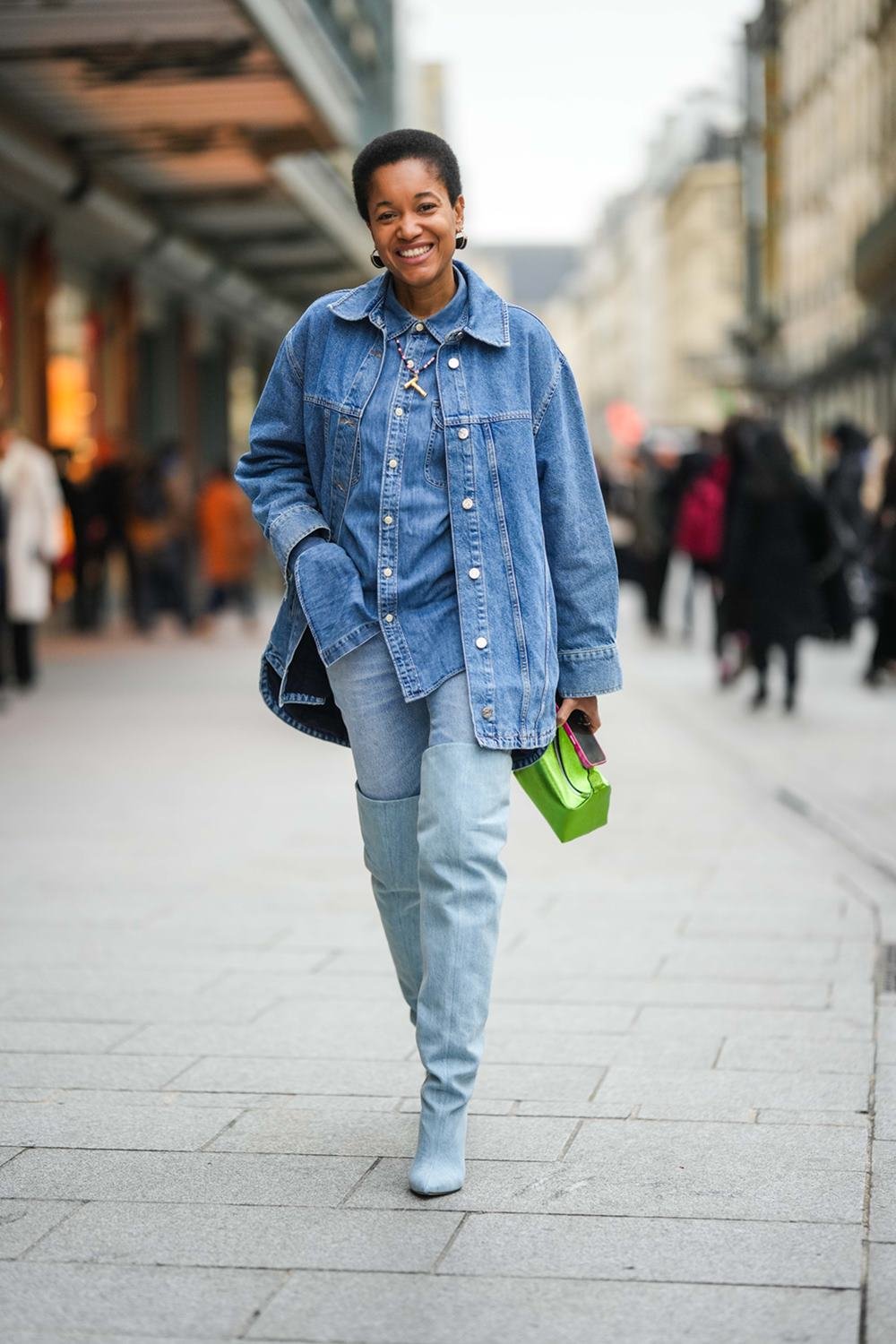 Tamu McPherson, uma mulher negra e de meia idade, com cabelo crespo curto, posa para foto andando nas ruas de Paris. Ela usa um roupa toda jeans: uma camisa de botão, uma jaqueta, uma calça e uma bota. - Metrópoles