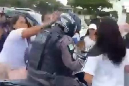 Imagem mostra momento em que mulher dá tapa no capacete de policial - Metrópoles