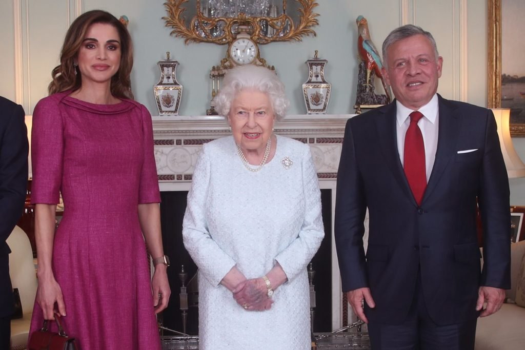Foto colorida de mulher parda e com vestido rosa ao lado de mulher idosa e com roupa branca. Um homem idoso está ao lado delas em um cômodo com objetos antigos - Metrópoles