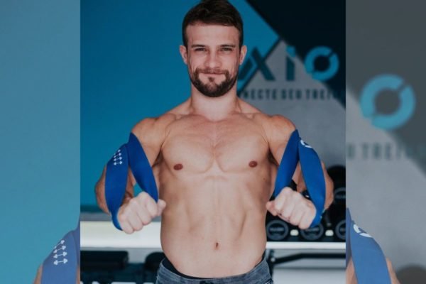 Foto colorida de homem branco flexionando elástico nos braços - Metrópoles