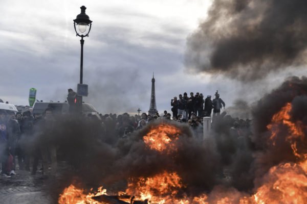 Torre Eiffel é vista enquanto manifestantes ateiam fogo em confrontos com a tropa de choque durante uma manifestação contra o plano do governo francês de aumentar a idade legal de aposentadoria em Paris