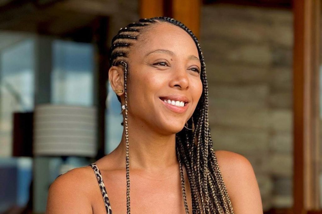 Imagem colorida mostra o rosto da cantora Negra Li, uma mulher negra com o cabelo com tranças, sorrindo - Metrópoles
