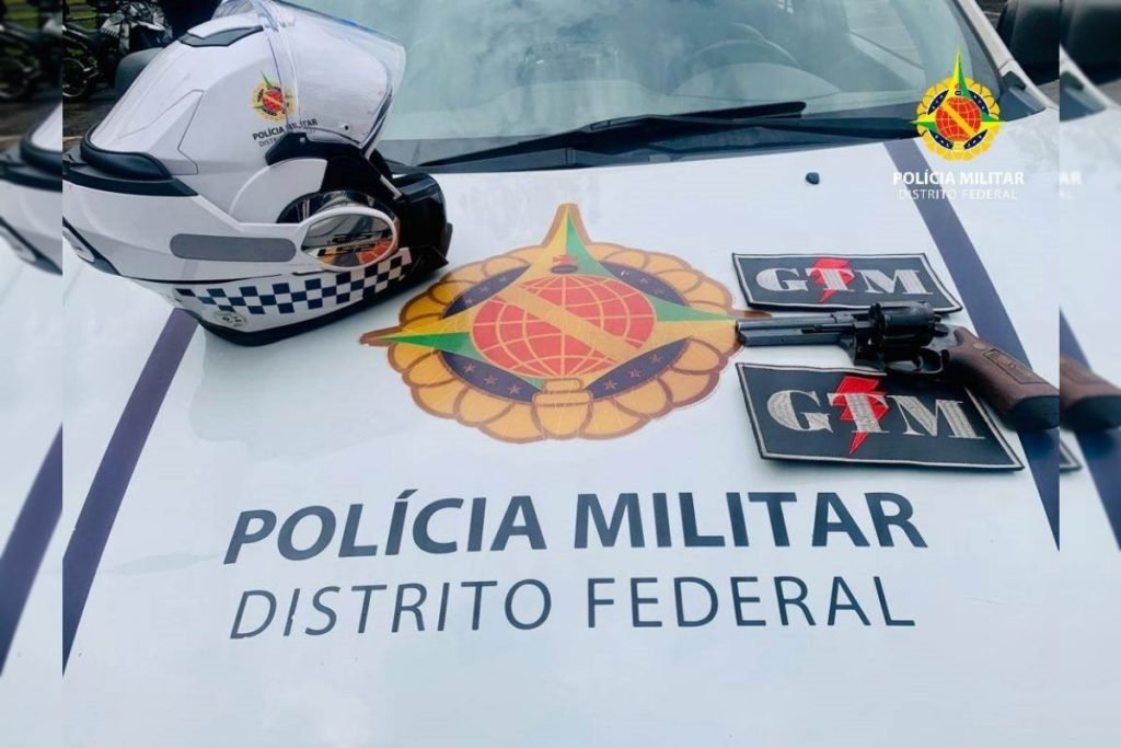 Capacete da PM e arma de fogo em cima de capô de viatura da PMDF