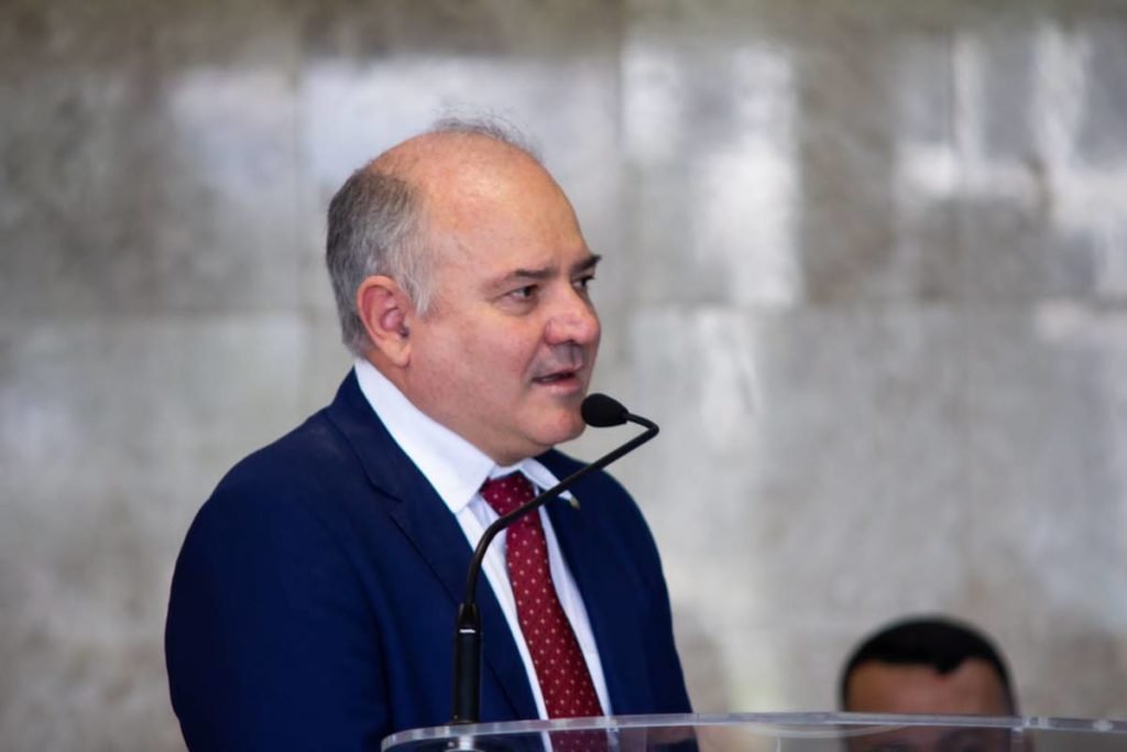Homem careca de terno azul e gravata vermelha