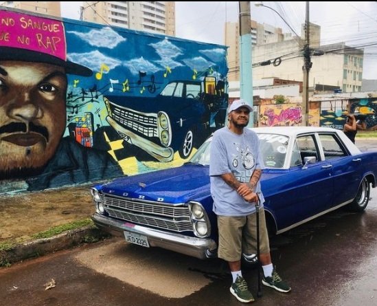 DJ Jamaika posa encostado em carro azul na rua