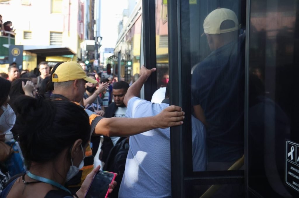 Imagem colorida de pessoas pegando ônibus