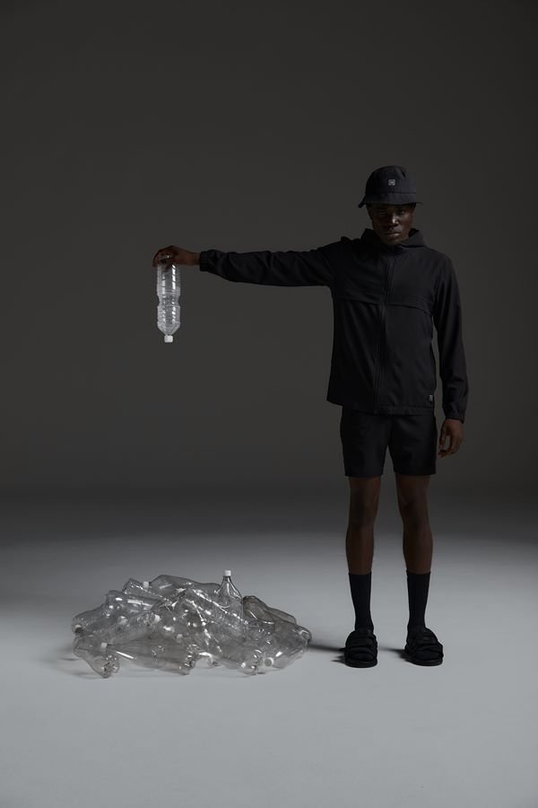 Na imagem com cor, modelo preto usa as novas peças da Oriba em fundo feito de garrafas pets - Metrópoles