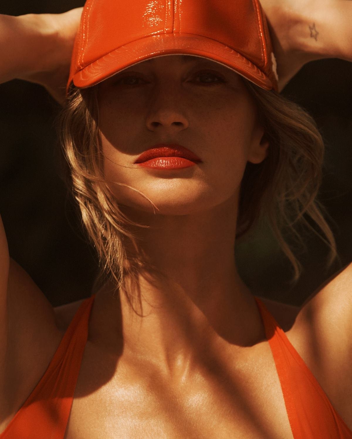 A modelo Gisele Bündche, uma mulher branca e de meia idade, com cabelo loiro ondulado, posa para foto em praia na Costa Rica. Os cliques são da revista Vanity Fair. Gisele usa um maiô laranja e um chapéu, também laranja, invernizado. - Metrópoles