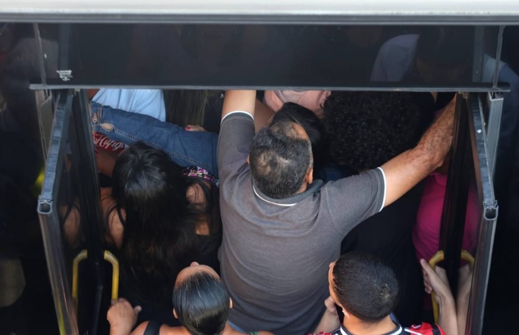 Imagem colorida de pessoas tentando entrar no ônibus