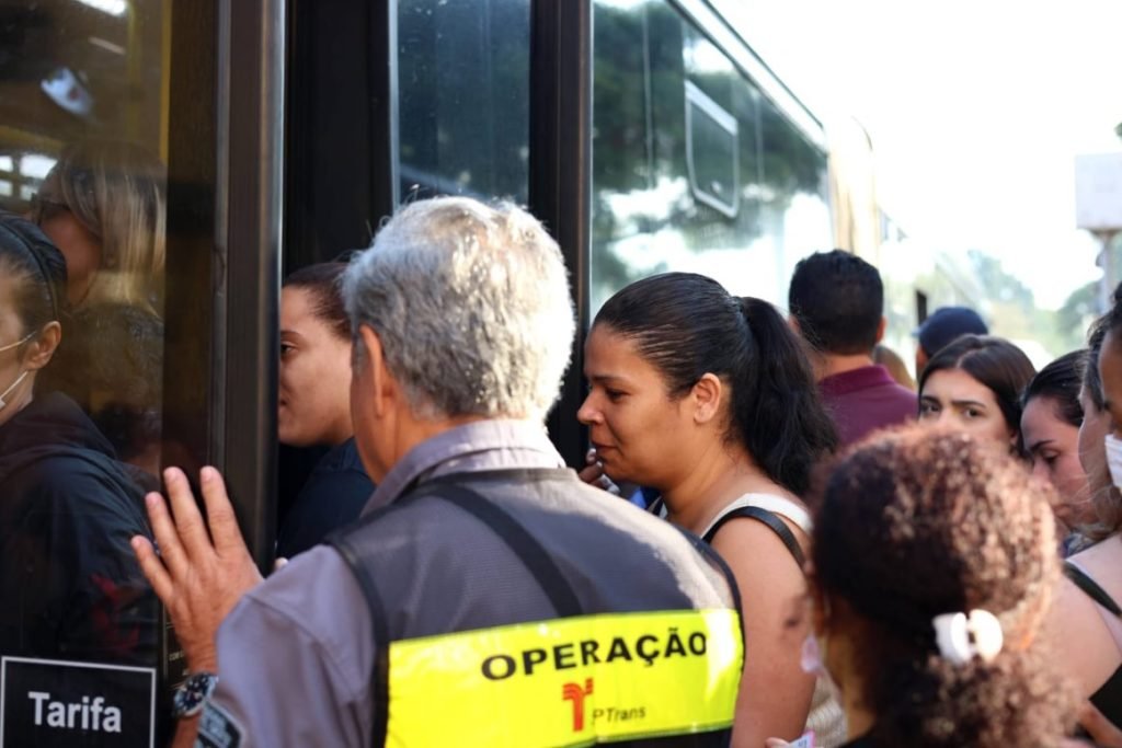 Imagem colorida de pessoas tentando entrar no ônibus