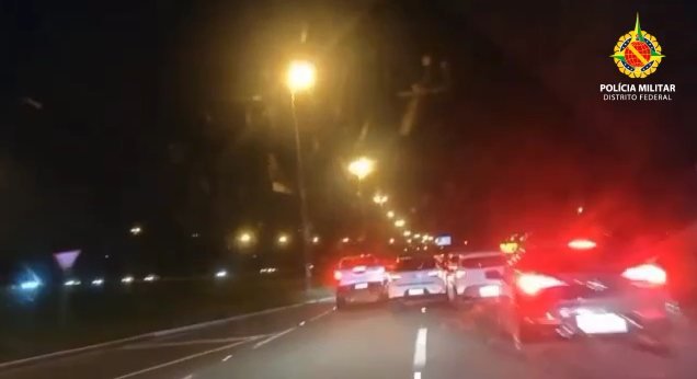 Carro branco circula por via a noite e tenta ultrapassar carros