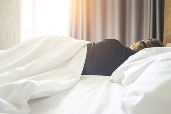 Imagem colorida: mulher deitada de costas em cama - Metrópoles