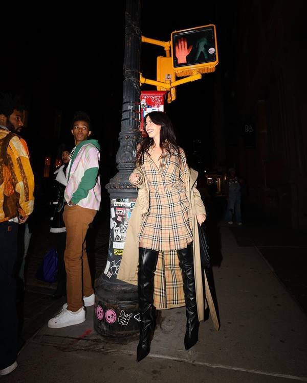 Camila Coutinho usa peças de roupa da marca Burberry em foto em filme. Ela está parada ao lado de um poste - Metrópoles 