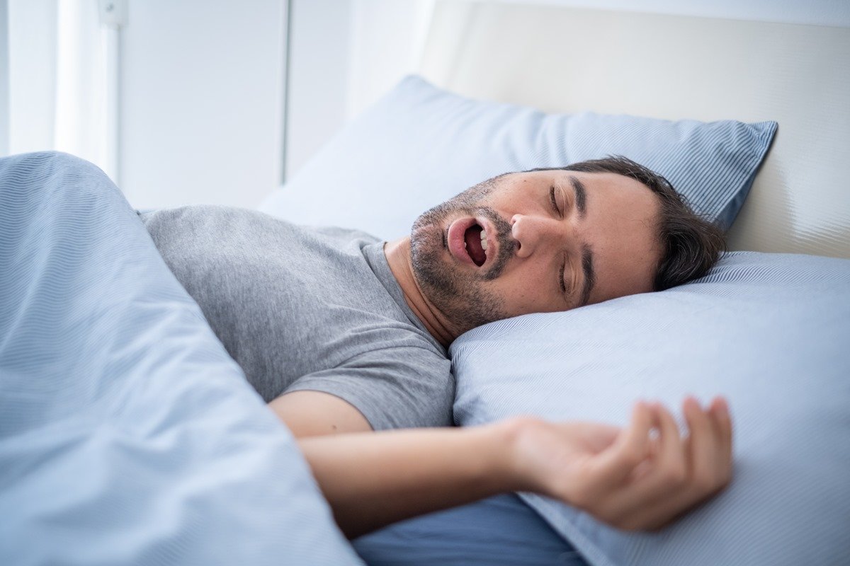Foto colorida de homem branco, com barba, rocando enquanto dorme - Metrópoles