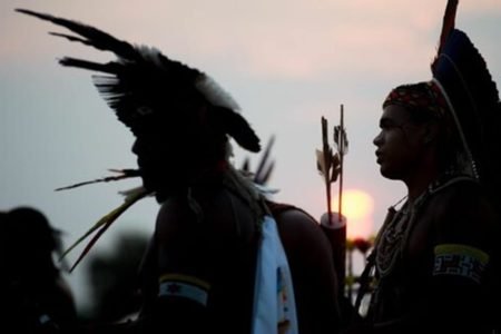 Foto mostra a sombra de duas pessoas indígenas - Metrópoles