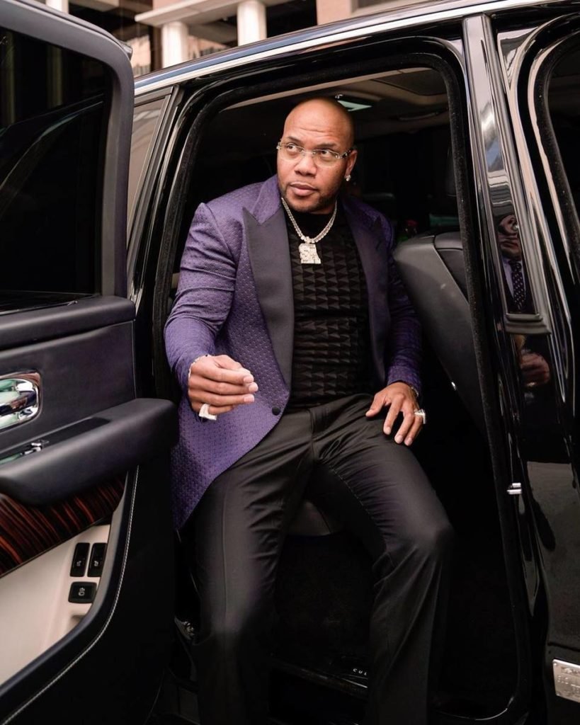homem de roupa preta e blazer roxo saindo de carro - metrópoles