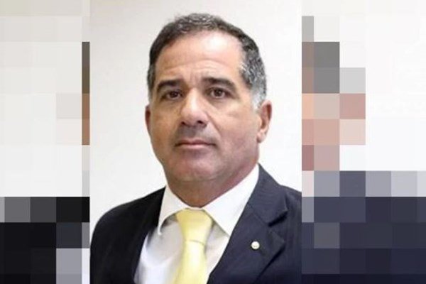 Fotografia colorida de homem de terno preto, camisa branca e gravata amarela