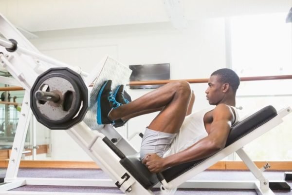 Homem fazendo exercicios de pernas em aparelho de academia - Metrópoles