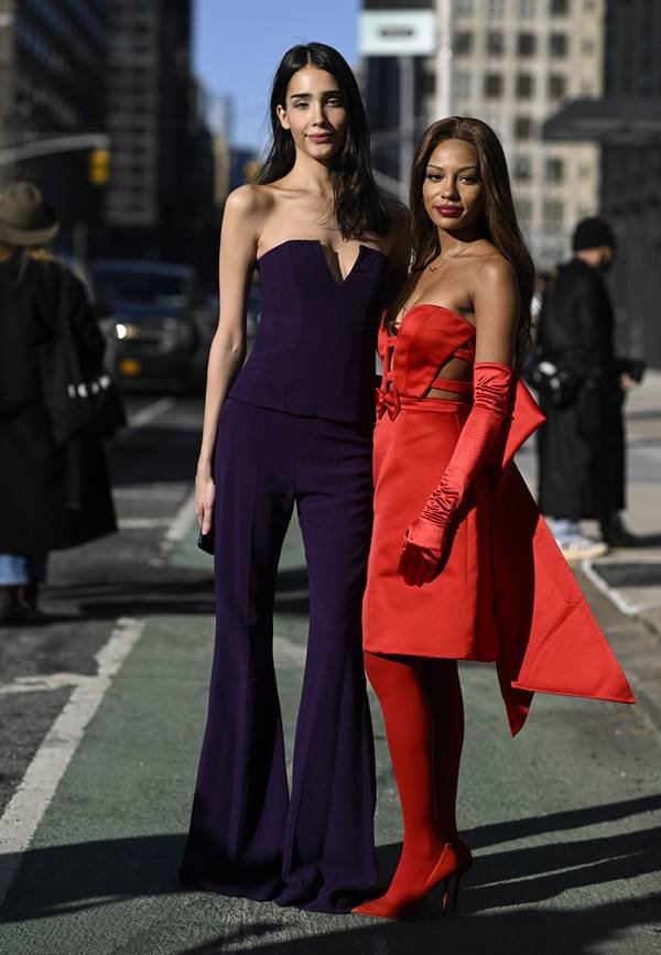 Na rua, mulheres usam looks sem alças. Um é roxo e o outro é vermelho, com luvas