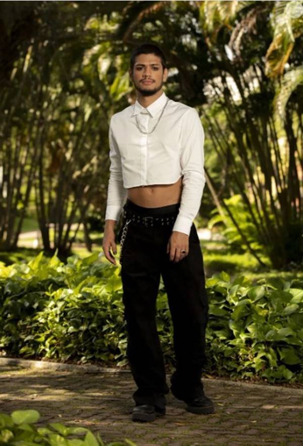 Against the backdrop of trees, Gabriel Santana wearing a short look with a social shirt and black pants - Metropoles