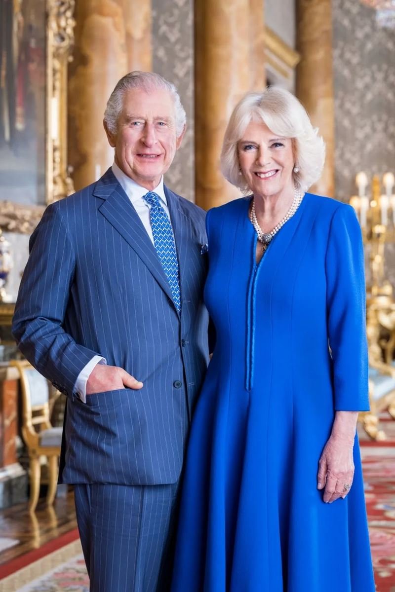 Foto colorida de homem idoso, branco, com terno risca de giz abraço a uma mulher branca, idosa e com vestido azul. Eles estão em uma sala com detalhes dourados - Metrópoles