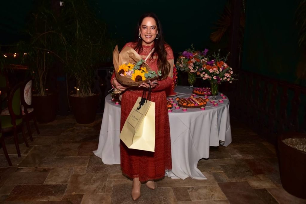 Silvia Abravanel posa com buque de flores e sacola de presente na mão - metrópoles