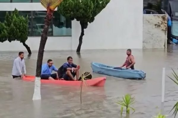 Foto colorida de hóspedes e funcionários saindo de hotel de caíque - Metrópoles