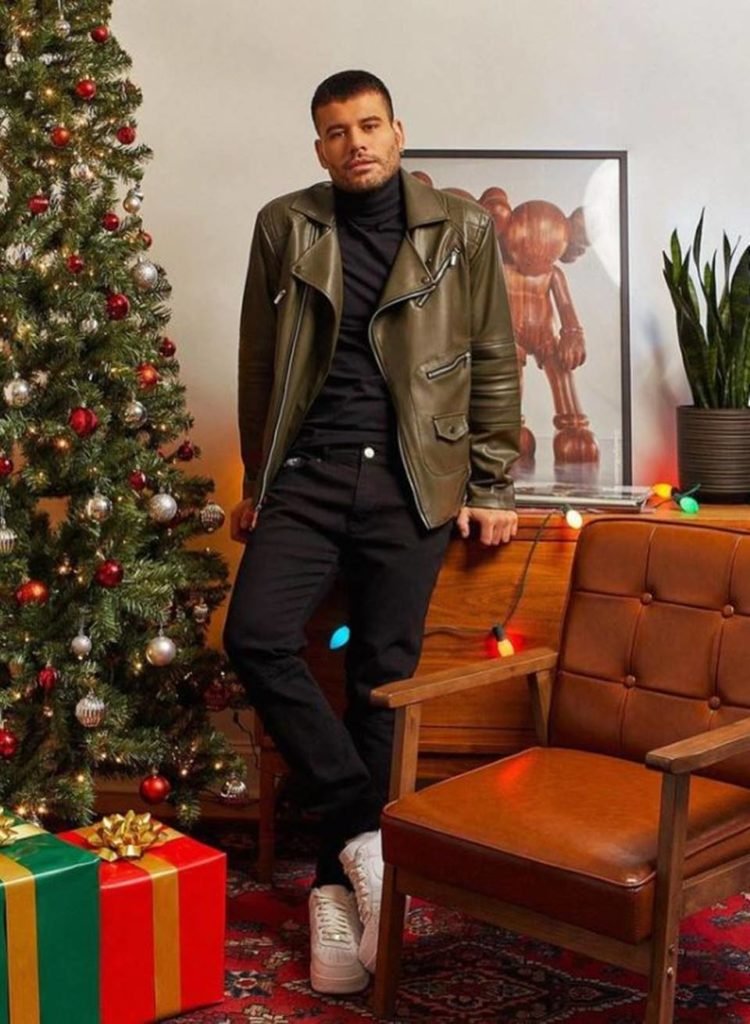 homem de roupa preta e casaco verde militar em sala decorada para natal - metrópoles