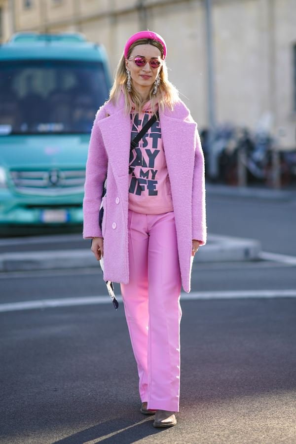 Mulher andando em calçada com roupas cor de rosa. Ela está caminhando e usando óculos de sol - Metrópoles