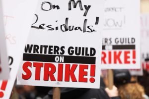 Foto colorida de cartazes sobre a greve de roteiristas em Hollywood - Metrópoles