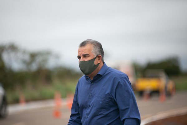 Fotografia colorida mostra homem de camisa azul e máscara escura