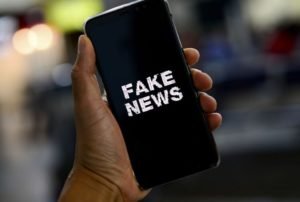 Pessoa segura celular com uma tela escrito "fake news" - Metrópoles