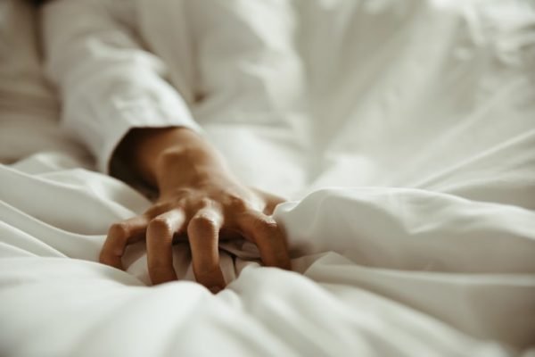 Orgasmo, excitação, mulher aperta os lençóis de cama - Metrópoles