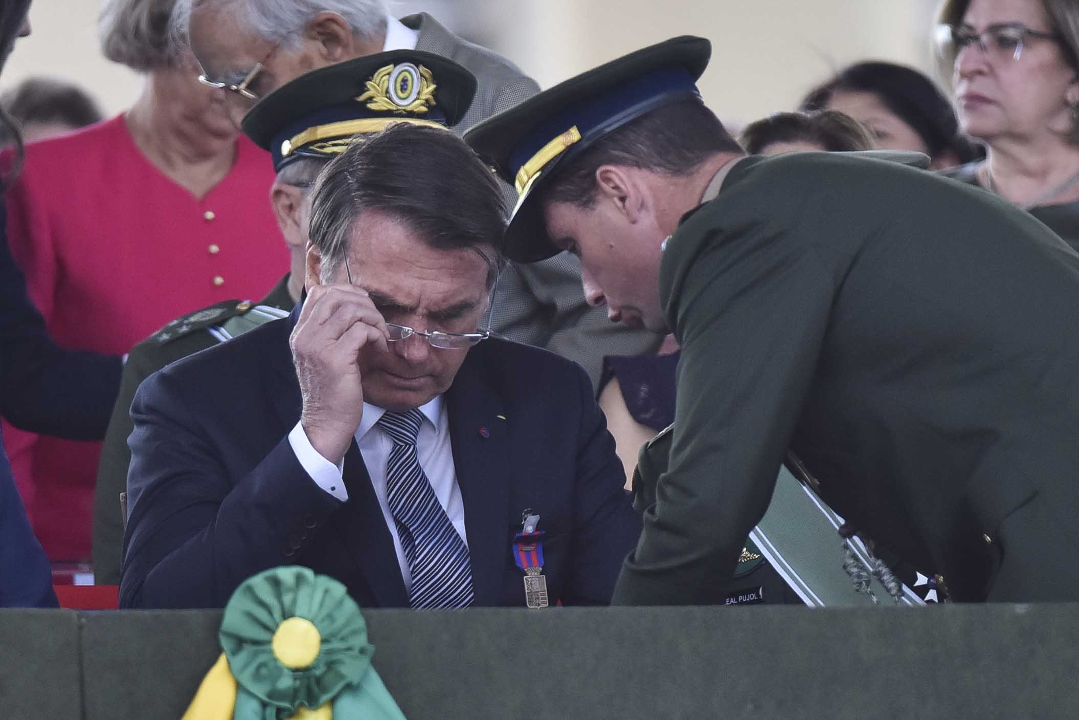 O presidente Jair Bolsonaro e Mauro Cid conversam durante participa da solenidade em homenagem ao dia do Soldado no QG do Exército