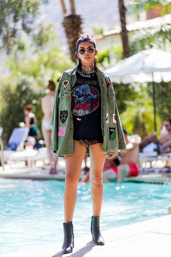 Mulher posando para foto em frente a uma piscina. Ela está usando camiseta, jaqueta e óculos de sol - Metrópoles