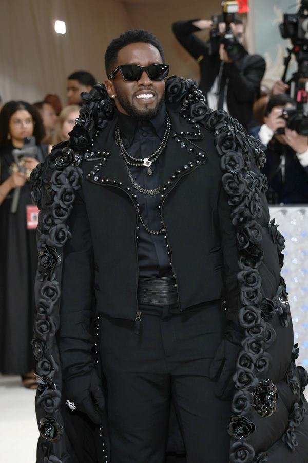 Na imagem com cor, um homem negro usando óculos, terno preto e casaco preto - Metrópoles