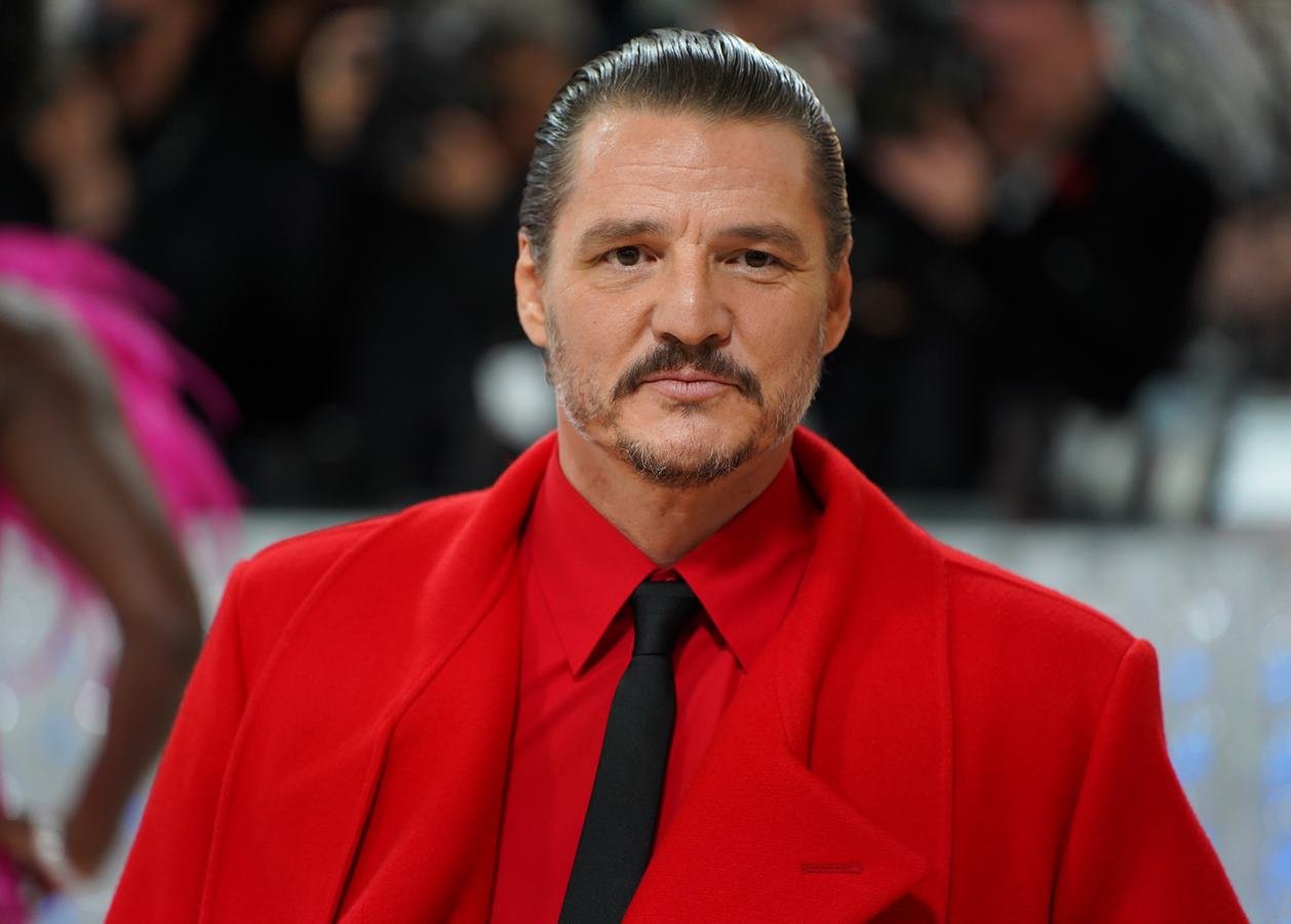Na imagem com cor, um homem branco com cabelos castanhos e bigodes, usando um casaco e camisa vermelhas - Metrópoles