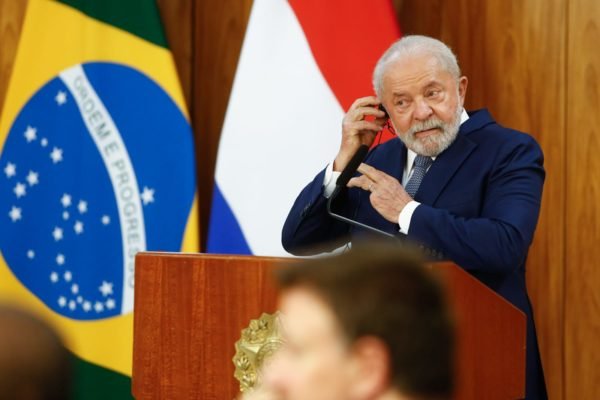 presidente Lula coloca fone de ouvido ao lado das bandeiras do brasil e Países Baixos