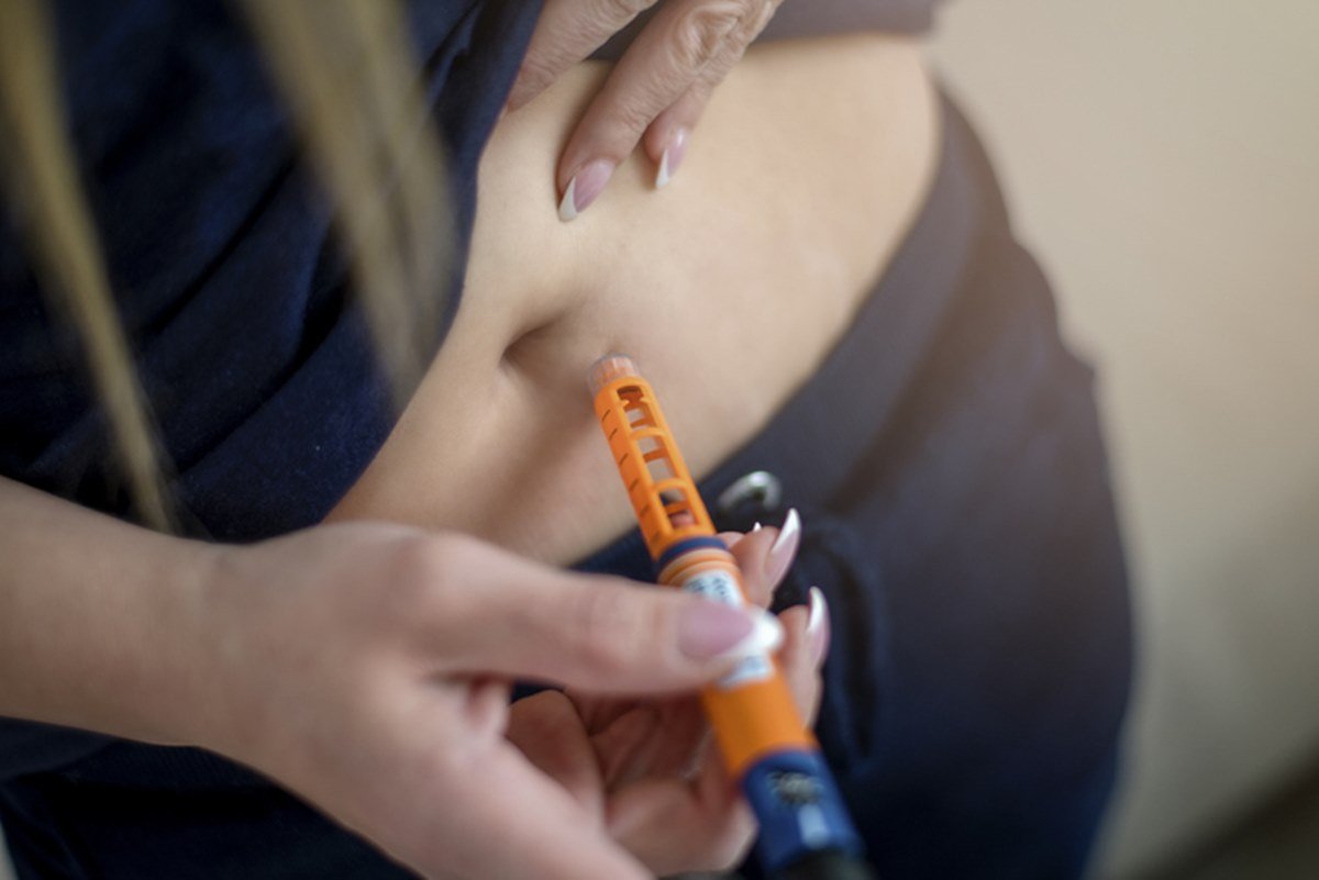 Imagem colorida: mulher aplica injeção de insulina na barriga