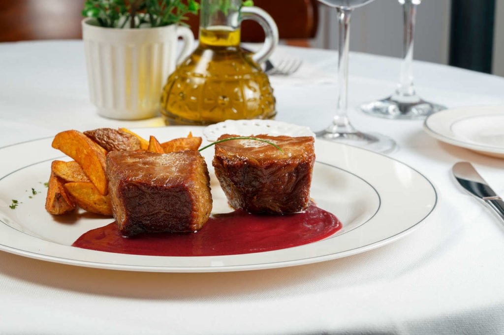 Na foto,um prato branco com carne e molho - Metróples