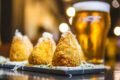 Na foto, três coxinhas com um copo de cerveja atrás - Metrópoles
