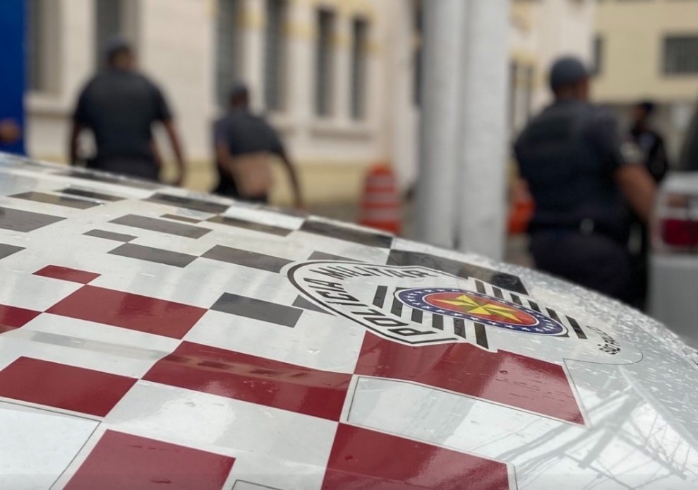 Imagem colorida do capô de uma viatura da Polícia Militar de SP. A peça é quadriculada em branco e vermelho com o logo da PM paulista - Metrópoles