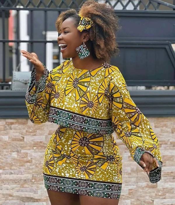 De lado e sorrindo, mulher negra usa look amarelo com estampa africana - Metrópoles