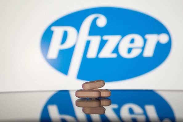 Foto mostra comprimidos em primeiro plano com a logo da Pfizer ao fundo - Metrópoles