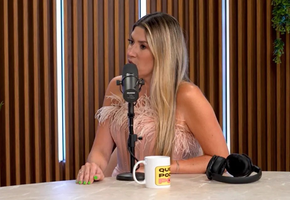 Foto de Dani Calabresa em podcast. Ela fala em microfone, sentada, apoiada em uma mesa - Metrópoles