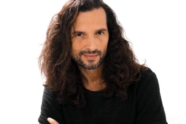 Foto colorida de Jeff Machado com cabelos longos e blusa preta - METRÓPOLES