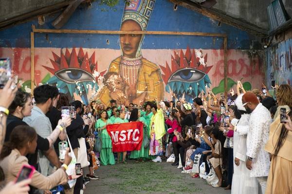 Grupo de pessoas em passarela de desfile segurando faixa vermelha do MSTC - Metrópoles